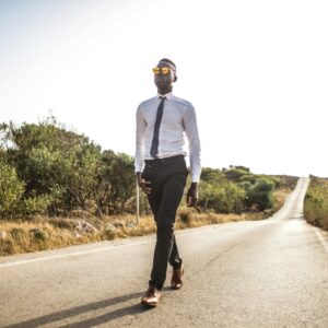 Man Walking on Roadway Under the Sun