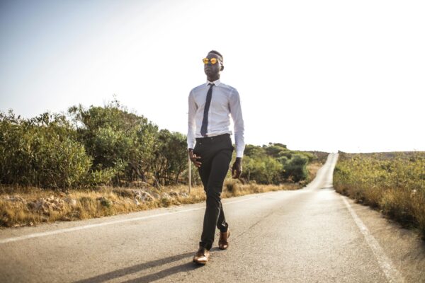 Man Walking on Roadway Under the Sun